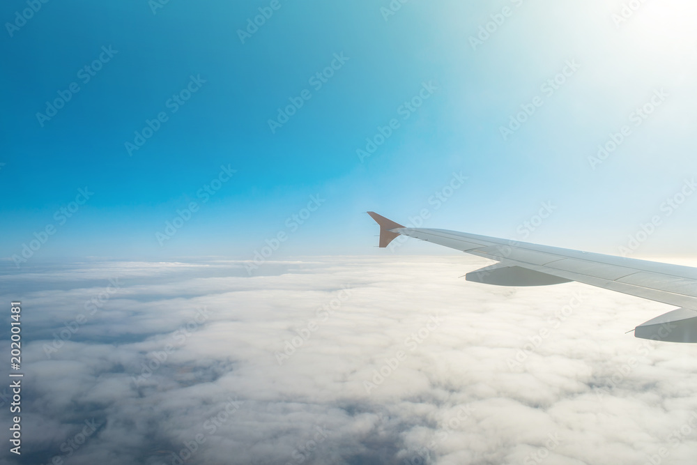 Fototapeta premium Wing view of the airplane, fluffy clouds on the skyline during climbing flight level.