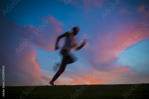 Colorful sunset view of a silhouette of a man running with motion blur. Slow shutter speed to enhance sense of movement.