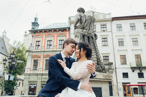 Elegant bride with groom walking near old catholic cathedral  © VAKSMANV