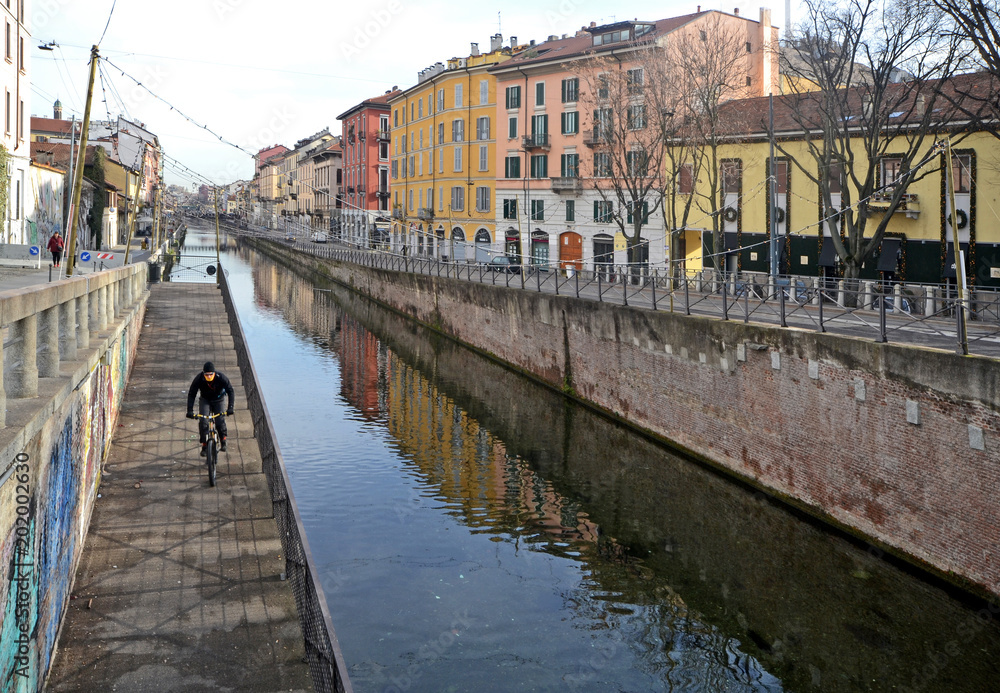 Milano, Italy, January 2018, old colorful buildings along the Naviglio river in the morning. A Cyclist trains