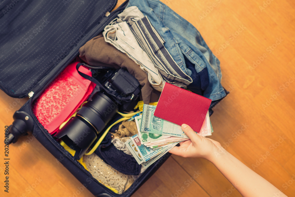 Female hands with Asian money and passport. suitcase with things on the floor.Travel concept Female hands with Asian money and passport. suitcase with things on the floor.Travel concept