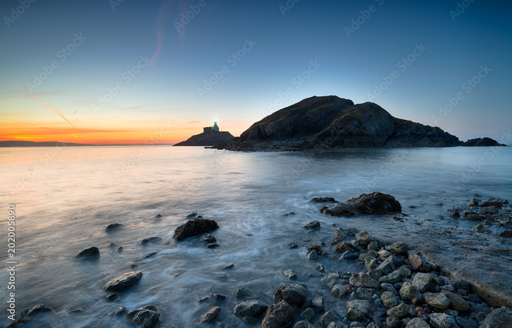 Stunning sunrise over The Mumbles lighthouse in Swansea Bay on the south coast of Wales Stunning sunrise over The Mumbles lighthouse in Swansea Bay on the south coast of Wales