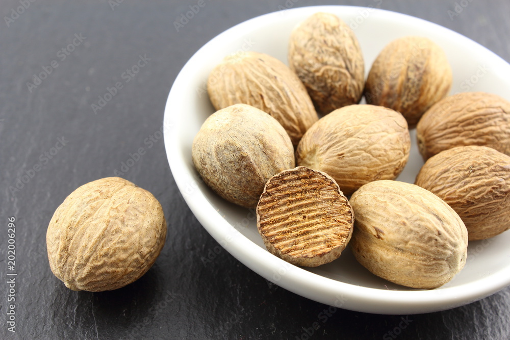 nutmeg seeds in a small white bowl nutmeg seeds in a small white bowl