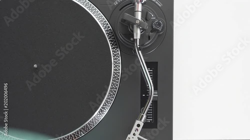 Label NU, Varna, Bulgaria - April 2018: Slide the side view to the hands of the DJ's girl put a green vinyl plate on rotating disc of the turntable and the needle the stylus, on a white background