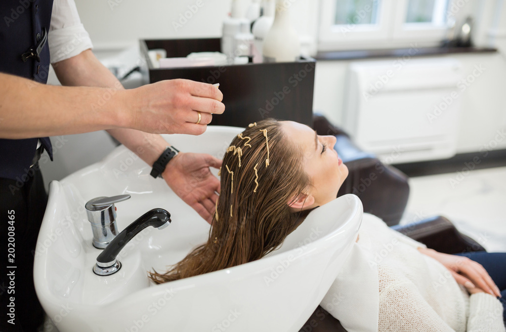 Hairdresser hands applying conditioner on client hair Hairdresser hands applying conditioner on client hair