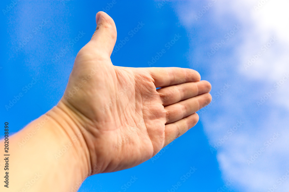 Male hand against a blue sky with clouds Male hand against a blue sky with clouds