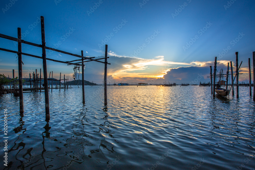 Sunset in the middle of Songkhla lake with beautiful sky reflecting on water surface and mountain in background.