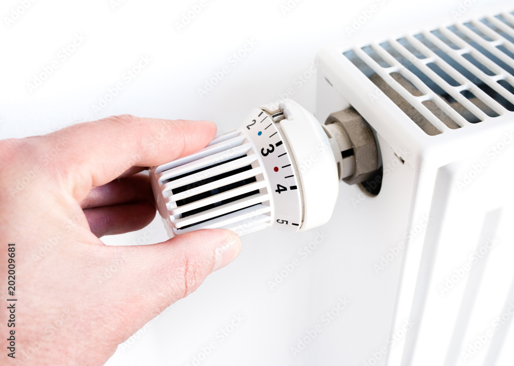 hand of man adjusting temperature on thermostat on radiator hand of man adjusting temperature on thermostat on radiator