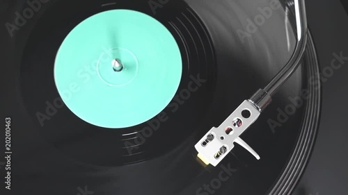 The vinyl record on DJ turntable record player close up. Black vinyl background with a green screen in the center. The rotating plate and stylus with the needle close-up. Loop. Macro. View from above