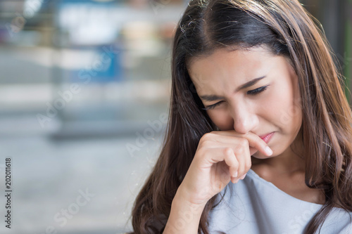 sick girl sniffle with runny nose; sick woman suffering from cold, flu, runny nose, trying to clear her nose; woman personal health care, pain, sickness concept; asian young adult woman model
