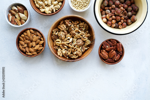 Variety of nuts on light concrete background Top view and empty space
