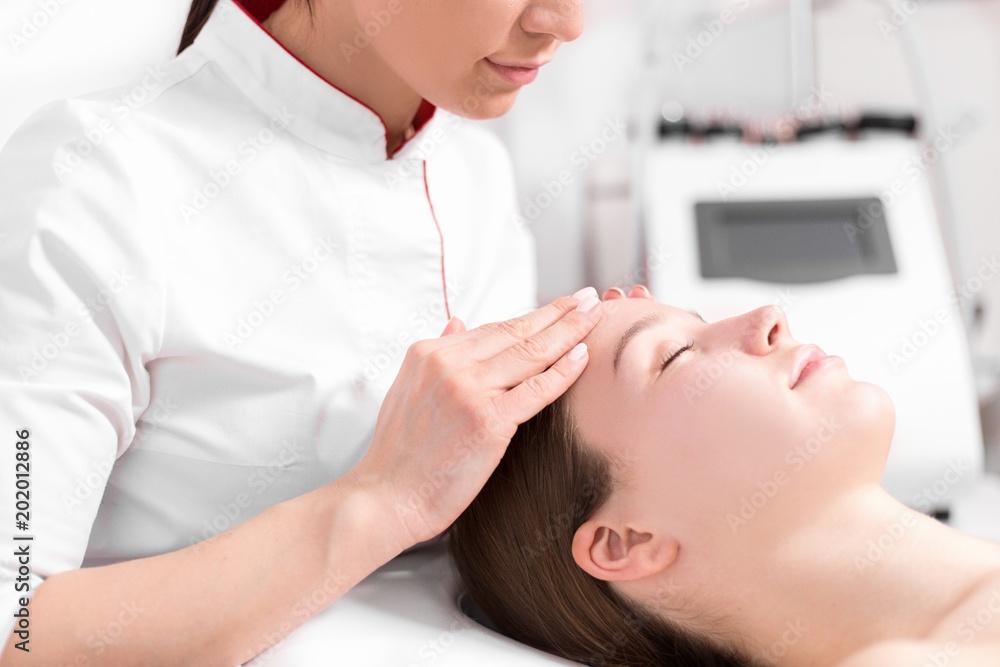 Cosmetologist massage therapist in the spa makes massage on the face of the girl