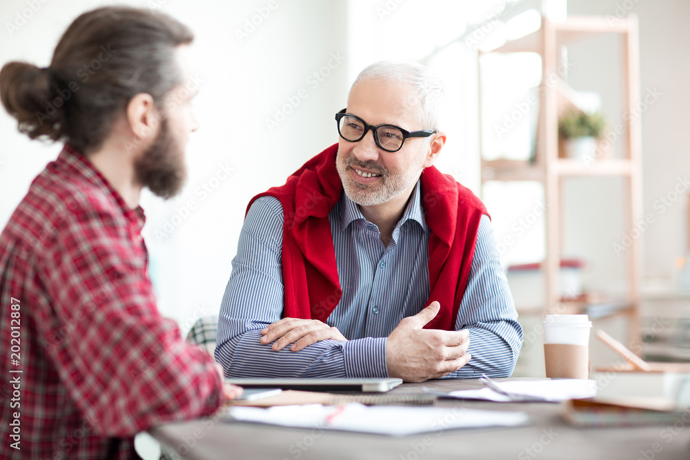 Smiling mature businessman communicating with his partner at the table Smiling mature businessman communicating with his partner at the table