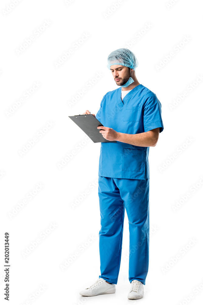 Thoughtful medical worker wearing blue uniform and writing in clipboard isolated on white Thoughtful medical worker wearing blue uniform and writing in clipboard isolated on white
