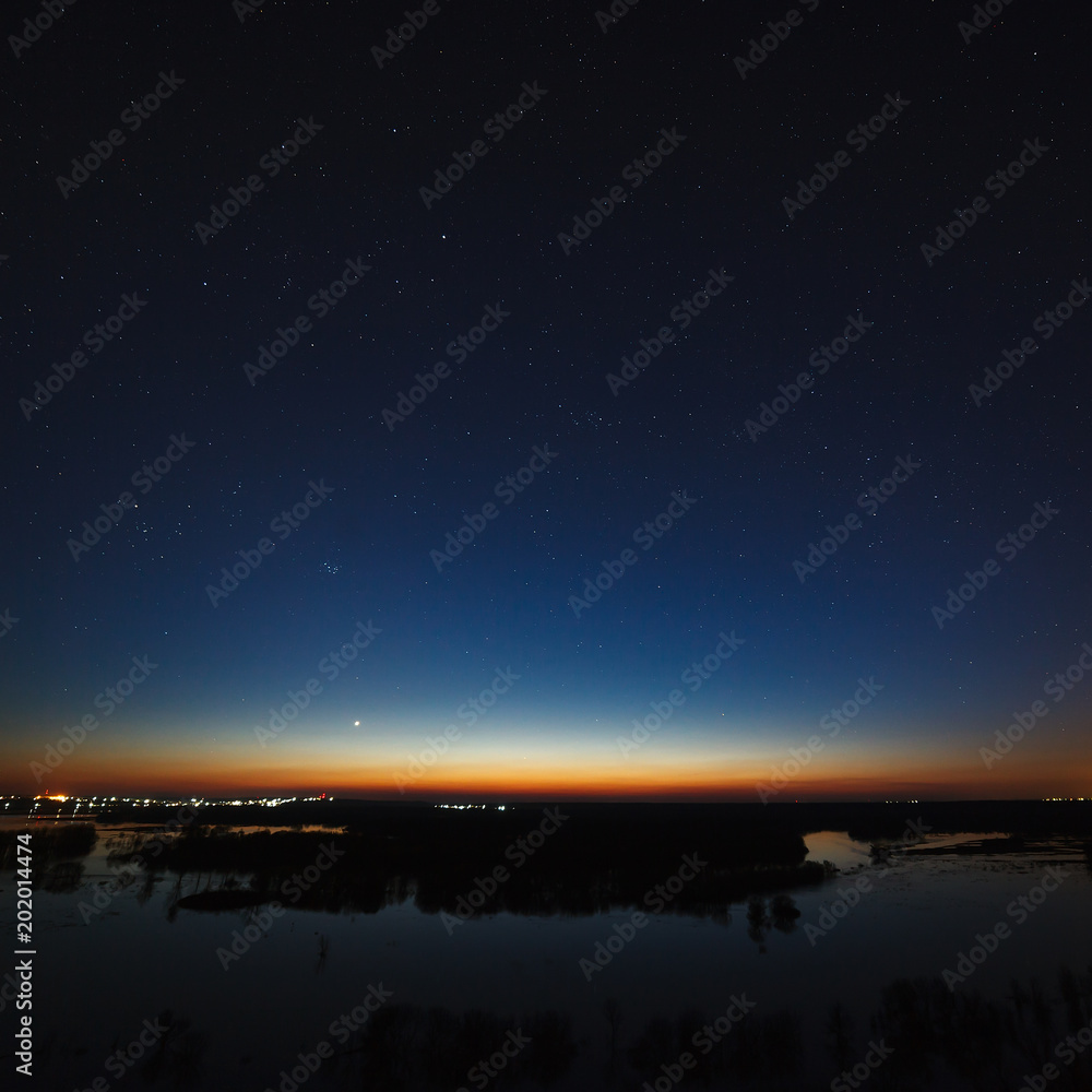 Night sky with stars above the river during the spring flood. View of the starry space.