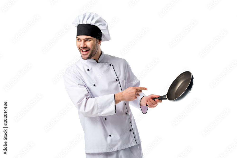 smiling chef in uniform pointing at frying pan in hand isolated on white smiling chef in uniform pointing at frying pan in hand isolated on white