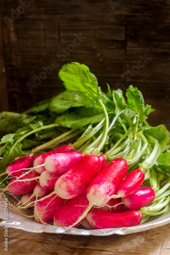 A bunch of radishes in an iron plate on a wooden background. Rustic style.