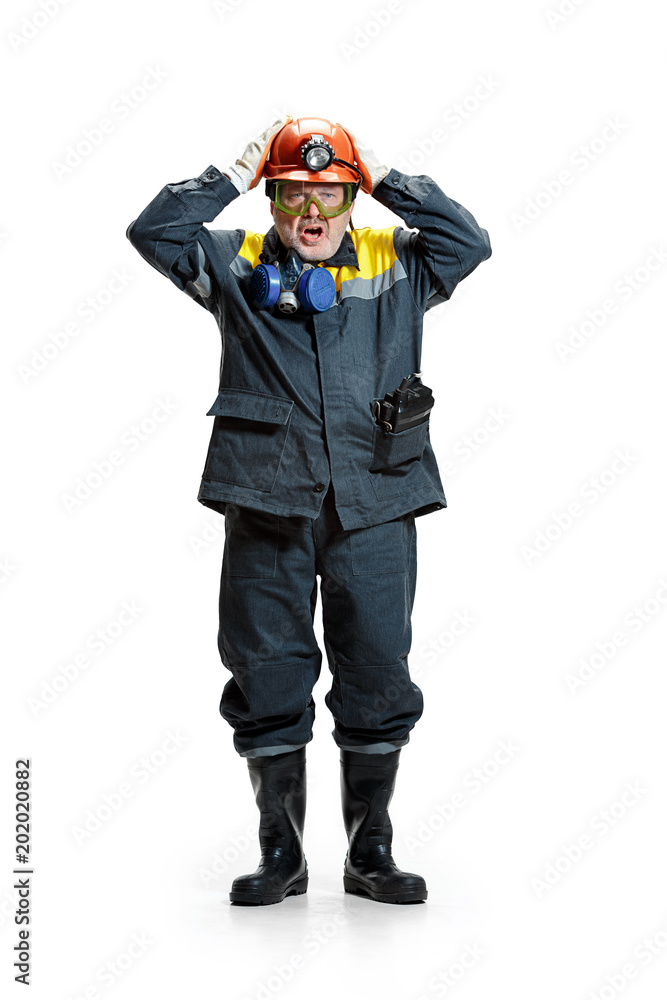 The studio shot of senior bearded male miner standing at the camera on a white background. The studio shot of senior bearded male miner standing at the camera on a white background.