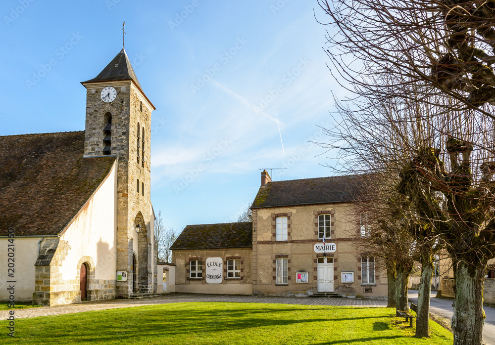 Φωτογραφία The church square of the small french village of Beauvoir in the department of Seine-et-Marne, 60 kilometers south-east to Paris, with its town hall, church and elementary school in between at sunset