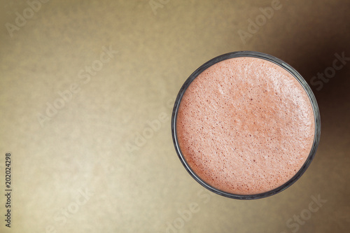 Glass cup of cacao with cream close-up on gold background. View from above