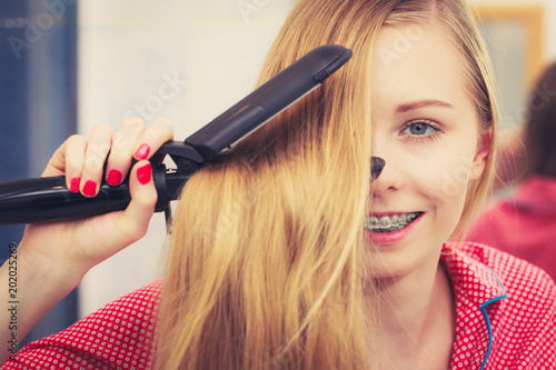 Woman straightening her long blond hair