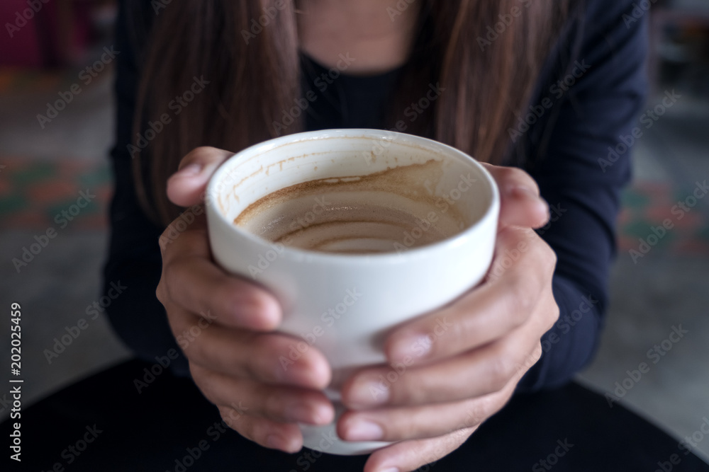 Closeup image of a woman holding a cup of coffee in cafe Closeup image of a woman holding a cup of coffee in cafe