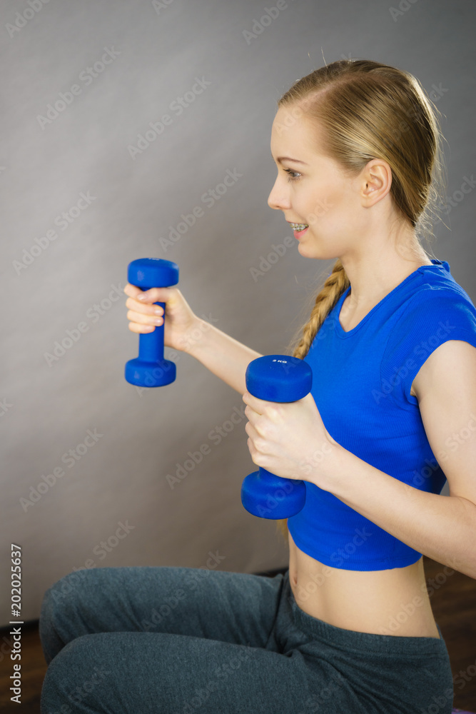 Teenage woman working out at home with dumbbell Teenage woman working out at home with dumbbell