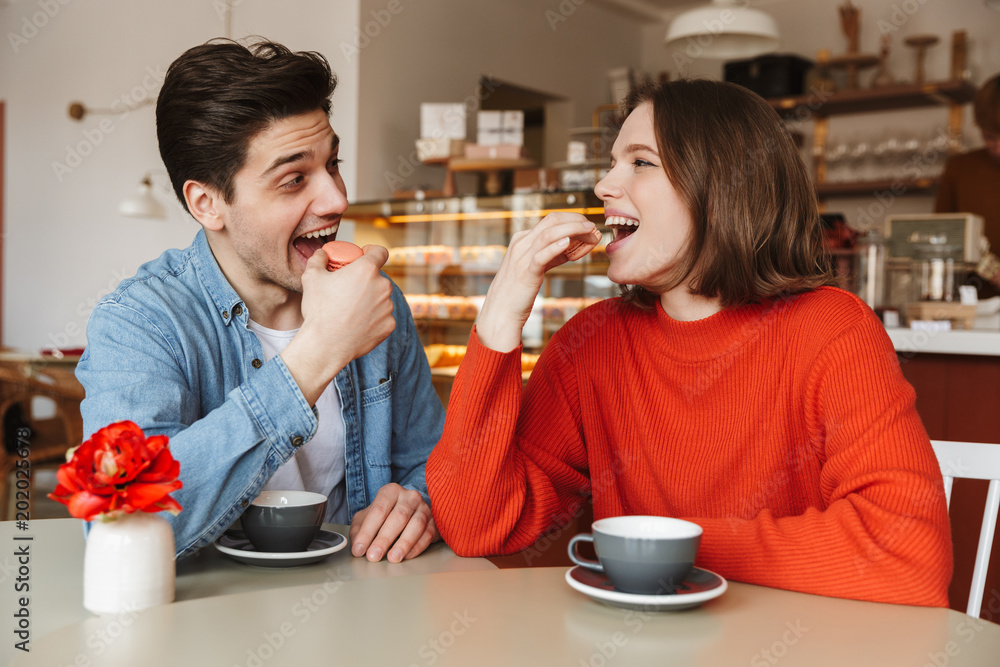 Φωτογραφία Portrait of happy couple man and woman dating in cozy bakery, and eating macaroo