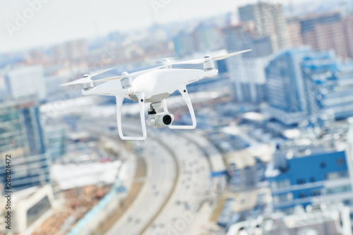 drone quadcopter with digital camera hovering over city