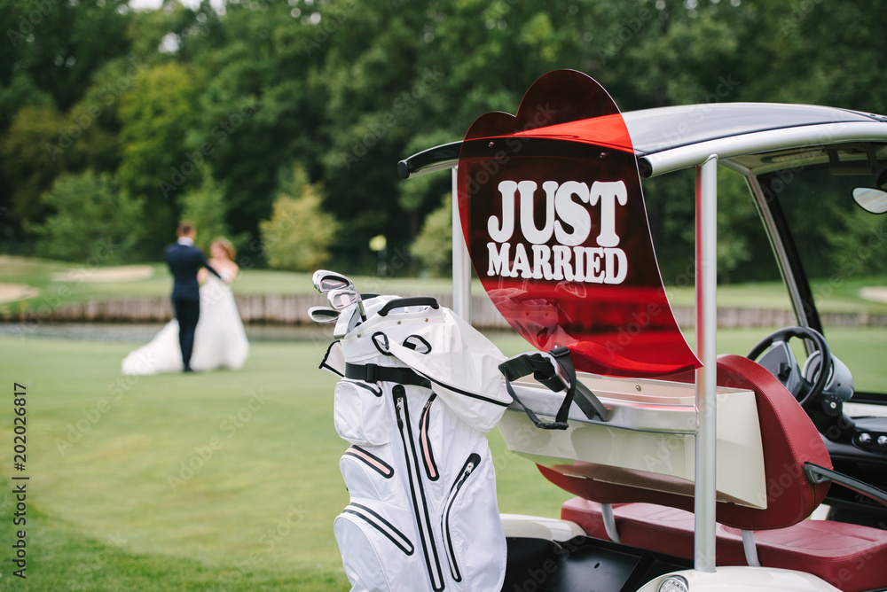 Just married sign on golf cart with dancing wedding couple in blur on ...