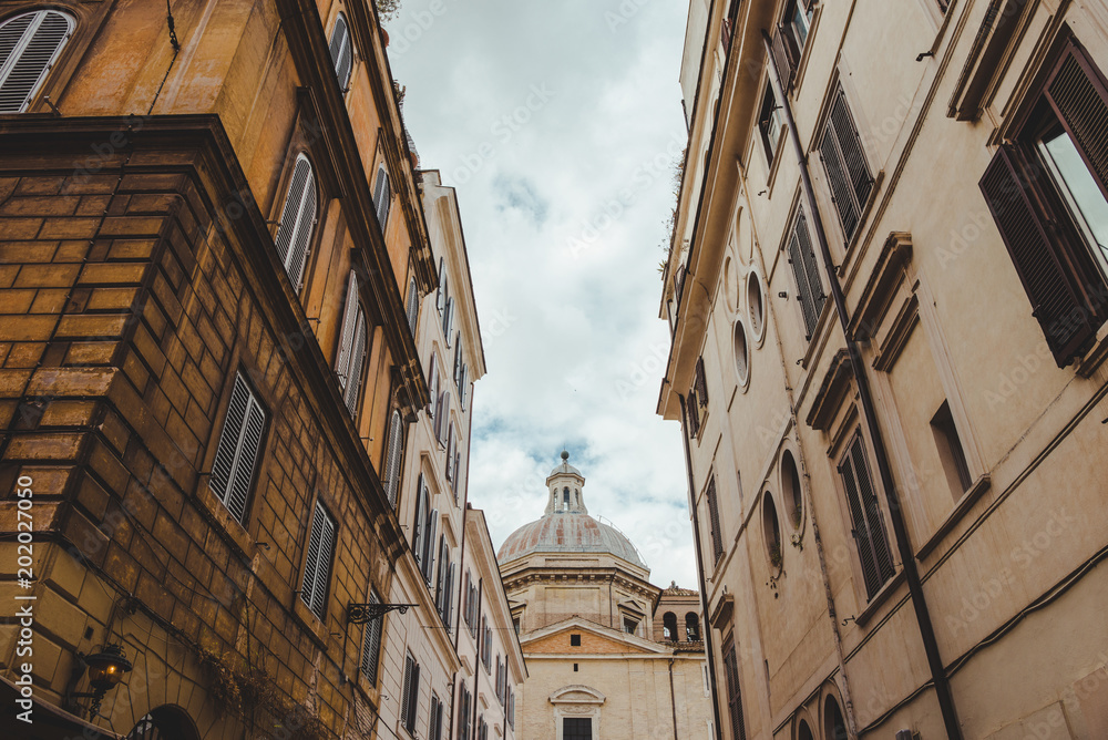 Fototapeta premium old buildings on street of Rome with cathedral on background, Italy