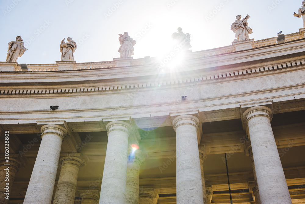 bottom view of statues with sunlight at St Peters Square in Vatican, Italy
