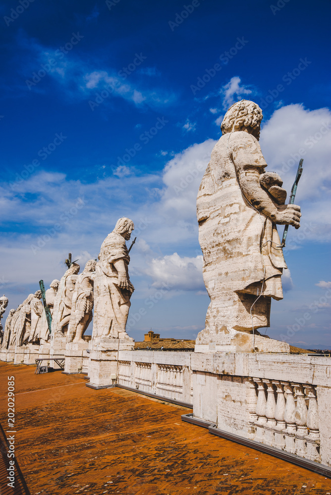 statues on top of St Peters Basilica on blue sky, Vatican city, Italy