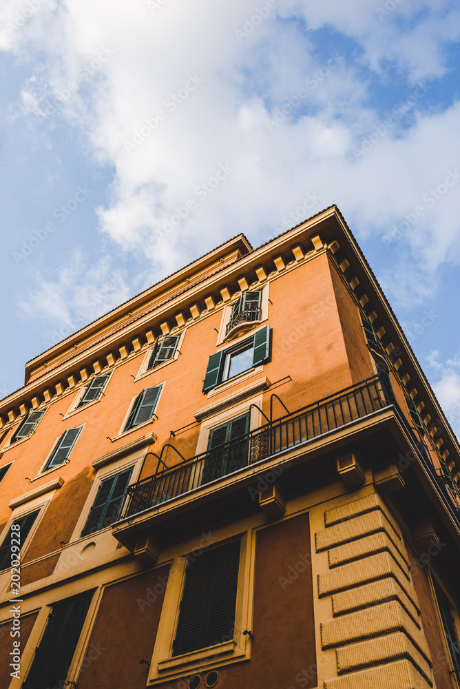 bottom view of orange building and cloudy sky in Rome, Italy