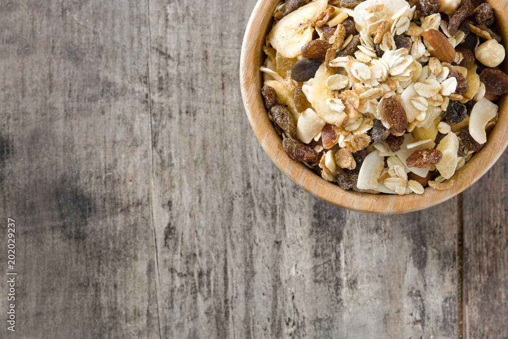 Muesli and dried fruit in wooden bowl on wooden table. Top view. Copyspace Muesli and dried fruit in wooden bowl on wooden table. Top view. Copyspace