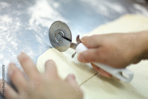 Quadro su tela Cutting a puff pastry with a pizza knife