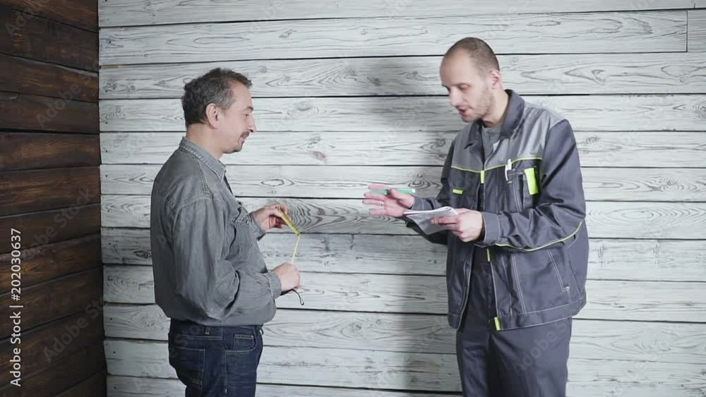 worker and the demanding customer to discuss and swear on the background of a wooden wall. Problem in construction. worker and the demanding customer to discuss and swear on the background of a wooden wall. Problem in construction.