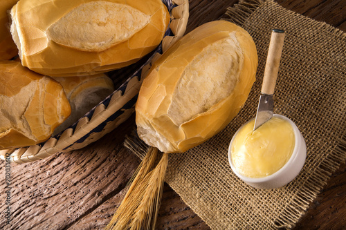 Basket of "French bread", traditional Brazilian bread with butter on wood background.