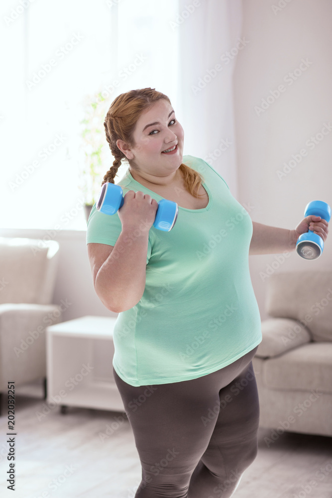 Workout routine. Obese young woman wearing sport shirt and leggings while  performing her workout routine foto de Stock | Adobe Stock