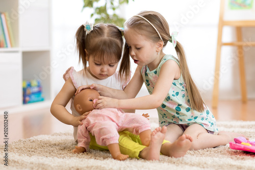 Obraz na plátně Two children girls playing doctor with a doll in kindergarten