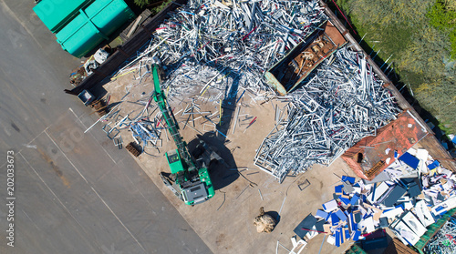 Photo aérienne d'une grue à pince mécanique, triant de la ferraille sur un site de recyclage