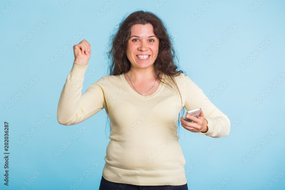 Happy beautiful woman holding mobile phone studio on blue color background. Happy beautiful woman holding mobile phone studio on blue color background.