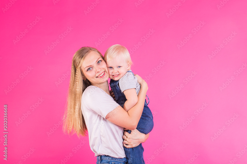 young mother and daughter having fun together on pink background young mother and daughter having fun together on pink background