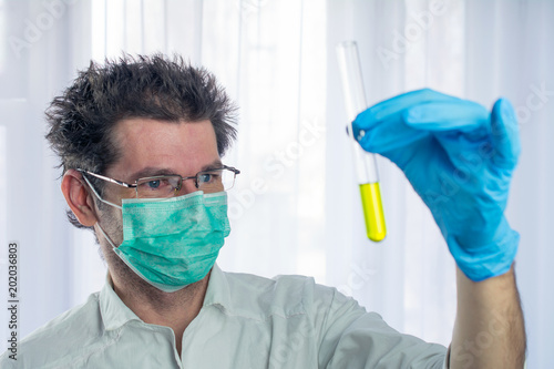 weird looking doctor holds yellow liquid test tube in his hand, concept dangerous medicine. selective focus