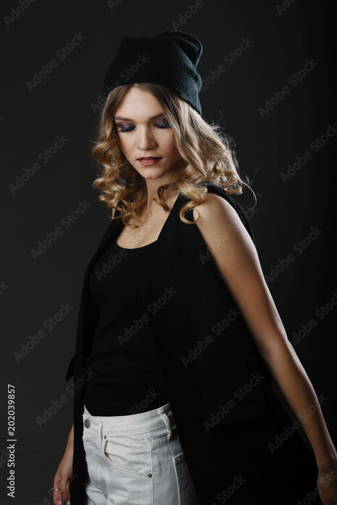 Elegant young woman with curly blonde hair wearing stylish clothes posing in the studio isolated on white background. Fashion portrait Elegant young woman with curly blonde hair wearing stylish clothes posing in the studio isolated on white background. Fashion portrait