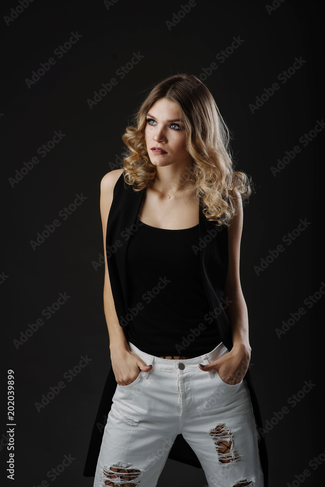 Beautiful fashion portrait of young blonde woman in stylish clothes posing isolated on black background Beautiful fashion portrait of young blonde woman in stylish clothes posing isolated on black background