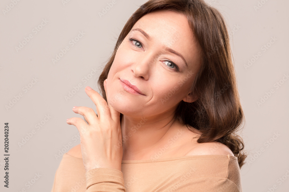 Charming brunette gently touching her face and oising on camera. Beauty concept. Mid age woman over 35 years old beauty concept. Charming brunette gently touching her face and oising on camera. Beauty concept. Mid age woman over 35 years old beauty concept.