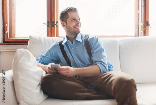 Handsome man sitting on sofa and texting