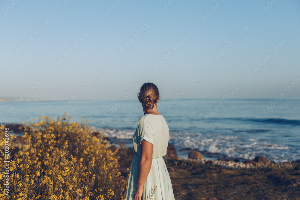 Woman in a Dress at the Beach at Dusk with Wildflowers