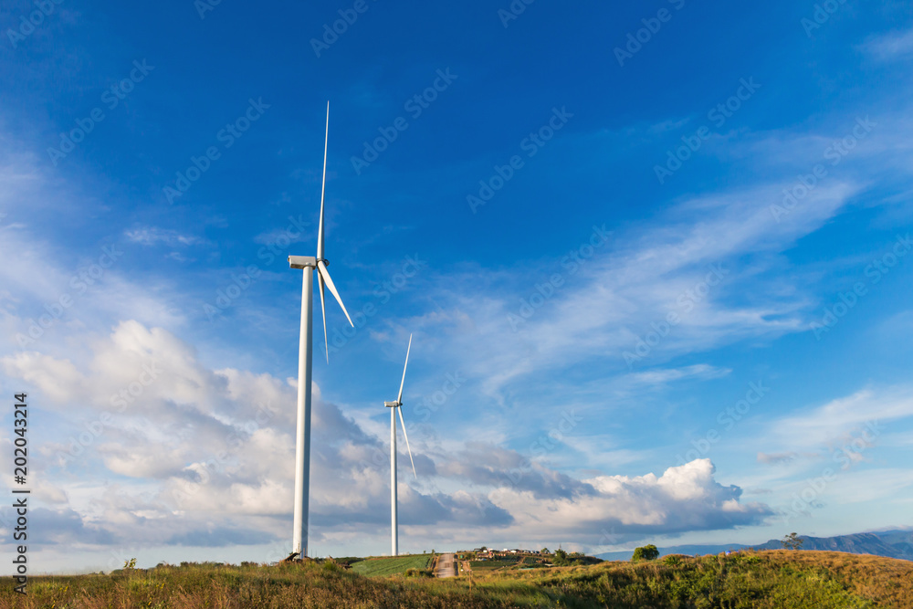 White wind turbine for alternative energy in day with blue sky background, electric clean power concept